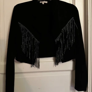 Svart mockajacka med fransar - Snygg svart mockajacka från Missguided med långa ärmar och croppad passform. Jackan har coola fransdetaljer 