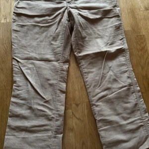 Beige manchesterbyxor från Lindex Jeans - Snygga bruna manchesterbyxor från Lindex i storlek 40. Byxorna har klassisk femficksdesign, dragkedja och dubbla knappar framtill. Materialet är mjukt och ger en retrovibe, något kortare i längden, perfekt för dig som gillar en avslappnad men ändå stilren look. Perfekta för hösten! 