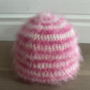 Virkad mössa helt ny - Superfin handvirkad mössa i mjuka rosa och vita nyanser! Tillverkad för hand och gjord av mohairblandningen ( ull/akryl/polyester) som gör mössan varm, lätt och otroligt mjuk. Passar perfekt för kyliga dagar och ger en gullig vibe till din outfit.