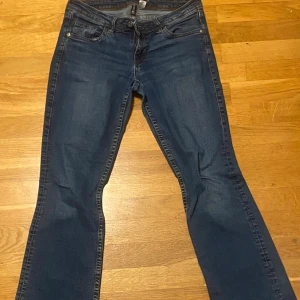 Blå bootcut jeans med broderade fickor - Snygga blå jeans med bootcut passform och klassisk femficksdesign. Baktill har byxorna broderade detaljer på fickorna som ger extra stil. Jeansen har låg midja och är tillverkade i mjukt denim-material. Perfekta för dig som gillar en avslappnad men trendig look.