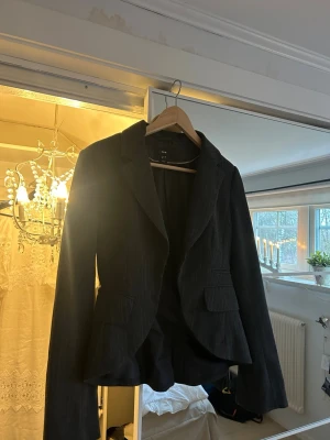 Svart kavaj från H&M - Snygg svart kavaj från H&M med diskreta ränder och klassisk krage.