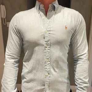 Jeansskjorta från Ralph Lauren - Säljer en jeansskjorta från Ralph Lauren med klassisk button-down krage och broderad logga på bröstet. Skjortan har smal passform och är tillverkad i mjuk bomull. Ser ut som ny. 