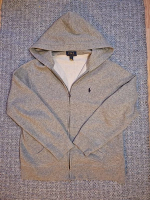 Grå Ralph Lauren hoodie  - Väldigt fin Ralph Lauren hoddie i grå. Den är mycket bra skick och typ ny. Använd i runt 1 månad🗓️. Den är i XS och passar dig runt runt 164 cm lång. Skriv om du har någon fråga👍