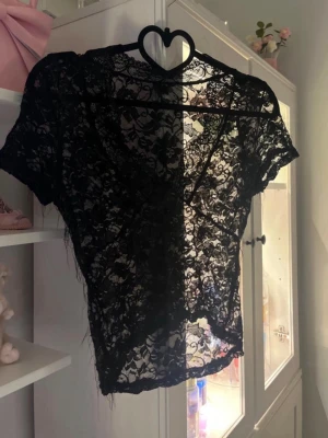 Svart spetstopp - Svart spets topp. Endast använd en gång men tvättad och därav blev det lite trådigt överallt på tröjan tyvärr (se bild 3). Storleken är L men sitter mer som en M