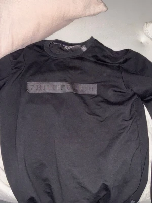 Svart långärmad t-shirt Philipp Plein - Svart långärmad t-shirt från Philipp Plein med Platinum Cut. Snyggt broderad logga framtill i svart ton och ribbad krage. Materialet känns som mjuk bomull och passformen är normal. Perfekt för dig som gillar stilrena designer och exklusiva märken. Det är Stolek M men passar S bra eftersom den sitter lite tajt på storlek M. Den är även knappt använder och ligger bara i garderoben skicket är som nytt 