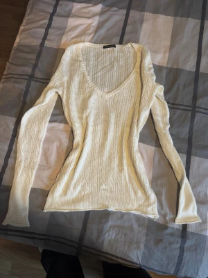 Vit stickad tröja från Brandy Melville - Säljer en vit stickad tröja från Brandy Melville med kabelstickat mönster och djup v-ringning. 