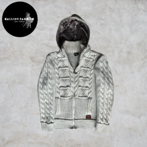 Cardigan med päls   - Grå stickad kofta med dragkedja och huva med kabelstickade ärmar, triangelformade detaljer fram och ett mjukt, lurvigt foder inuti huvan. Storlek L men kan även passa M. Hör av dig för mått vid osäkerhet.                                                      ~                                                                            Nypris okänt, liknande säljs för cirka 700-1000kr+ | Vårt pris: 799 kr. Alla följare får rabatt! 