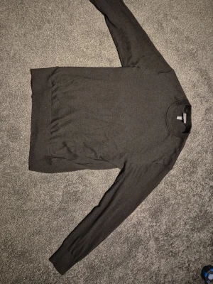 Svart Stickad Tröja - H&M - Svart stickad tröja från H&M i mjuk bomull. Tröjan har lång ärm, ribbade muddar och klassisk rund krage. Regular passform.