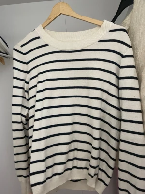 Randig tröja från Part Two - Snygg vit tröja med svarta horisontella ränder från Part Two. Klassisk rund halsringning och långa ärmar. Perfekt för en chill och stilren look. Mjuk och skön stickad känsla som passar året runt.