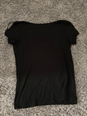 Svart topp med rosett från lager  157 - Säljer en svart topp från lager 157 i storlek S. Toppen har korta ärmar och en snygg detalj med en stor rosett i satinmaterial på ryggen, samt en öppning under rosetten. Hela toppen har en tajt passform.💕OPPS HAR 2 STYCKEN