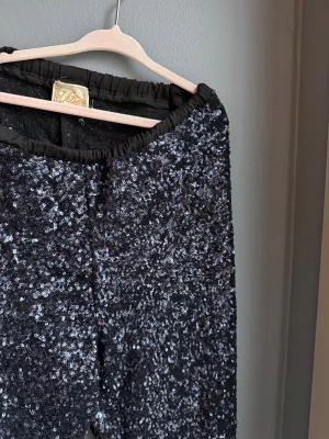 Svarta paljettleggings från Valene - Glittriga svarta leggings från designern Valérie Aflalo , täckta med paljetter. Elastisk midja och sitter tight längs benen. 