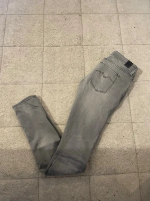 Replay Hyperflex grå jeans - Säljer ett par grå Replay Hyperflex jeans med skinny fit och klassisk femficksdesign. Jeansen har stretchigt material för extra komfort och snygga detaljer på bakfickan. Perfekt för dig som gillar stilrena och moderna jeans.