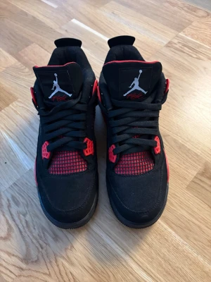 svart/röd sneakers - Säljer ett sneakers i svart och rött med klassisk Jumpman-logga på plösen. Skorna har snörning, meshdetaljer och en platt sula. Ovandelen är i mocka och syntet, med röda detaljer på sidorna och runt snörningen. Perfekt för dig som gillar streetwear och ikoniska modeller.