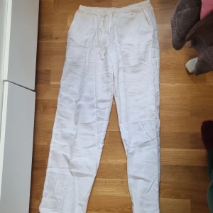 Vita linnebyxor från Gina Tricot - Snygga och luftiga vita linnebyxor från Gina Tricot med elastisk midja och snörning. Perfekta för varma dagar, med avslappnad passform och raka ben. Byxorna har fickor i sidorna och är tillverkade i mjukt linnematerial.