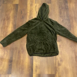 Mörkgrön fleece hoodie - Mysig mörkgrön hoodie i fluffig fleece med huva och stor magficka. Perfekt när du vill vara extra bekväm och hålla dig varm. Långärmad och loose fit för en avslappnad stil.