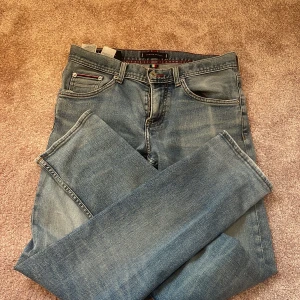 Tommy Hilfiger ljusblå jeans TH Flex - Snygga ljusblå jeans från Tommy Hilfiger med TH Flex-teknologi för extra stretch och komfort. Klassisk femficksdesign med röd detaljsöm vid myntfickan och logotyp på knappen. Passar dig som vill ha stil och rörelsefrihet.