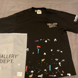 Svart Gallery Dept t-shirt Tokyo - Svart t-shirt från Gallery Dept med tryck 'TOKYO JAPAN' på bröstet och färgstänk i vitt, guld, rött, blått och lila på framsidan. Rund hals och korta ärmar, samt tryck på ena ärmen. Perfekt för dig som gillar streetwear och unika detaljer.