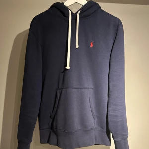 Polo Ralph Lauren hoodie - |Tja! En otroligt snygg och eftertraktad Polo Ralph Lauren hoodie i en skön färg ❗️| Skick 9/10 otroligt bra skick☑️| Storlek: M , sitter som M/S, sitter bra på mig - 189cm 73kg📏| Nypris: ca 2000kr💵| Färg: marinblå, som på bilden💙| Fraktar spårbart via postnord eller instabox📦| Hör av er för mer information!|