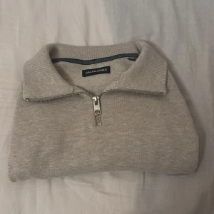 Beige stickad half zip-tröja Jack & Jones - Snygg beige stickad tröja från Jack & Jones i storlek S. Tröjan har en klassisk krage och half zip-dragkedja framtill. Använts ett fåtal gånger. Pris kan diskuteras!