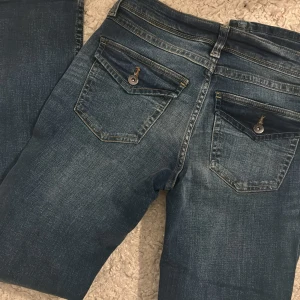 Lågmidjade jeans  - Lågmidjade jeans med knappar på bakfickorna. Använda 1 gång så nyskick! 