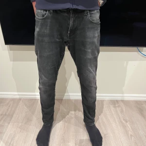 Svarta jeans från G-Star RAW - Säljer ett par svarta jeans från G-Star RAW med snyggt tvättad look och klassiska fem fickor. Jeansen är slim fit och normal passform, med detaljerade bakfickor och logopatch i midjan. Perfekta för dig som gillar en stilren och modern vibe.