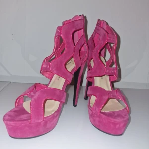 Rosa stilettos från Sugarfree shoes - Säljer ett par statement pumps i gorgeous pink med höga klackar och platåsula. Skorna har öppen tå, snygga utskurna detaljer och dragkedja bak. Helt nya.