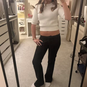 Vit croppad stickad tröja från Zara - Superfin vit croppad stickad tröja från Zara med halvlånga ärmar och rund hals. Tröjan har en ribbad kant nedtill och vid ärmslut, vilket ger en snygg och modern look. Perfekt att styla med höga jeans eller kjol.