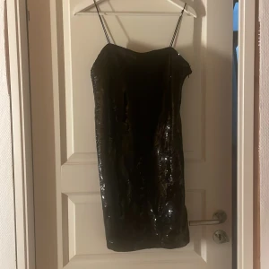 Svart glittrig kort klänning - Svart kort klänning med tunna axelband och glittriga paljetter