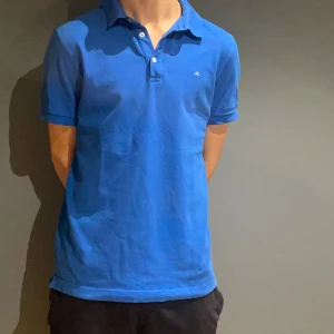 Blå pikétröja från J.Lindeberg M - Tja! Säljer en snygg blå pikétröja från J.Lindeberg i regular fit. Klassisk krage, tre knappar och diskret broderad logga på bröstet. Tillverkad i mjuk bomull som känns skön mot huden. Perfekt för en clean och sportig stil. Finns ett par fläckar på piken. Hör av er vid frågor :)