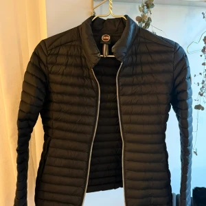 Svart pufferjacka från Colmar / Florida down jacket - Snygg svart pufferjacka från Colmar med horisontella sömmar och diskret logga på ärmen. Jackan har dragkedja framtill och en stilren, smal passform. Perfekt för kyliga dagar och enkel att matcha med olika outfits. Storlekarna är konstiga men det är en vanlig 34