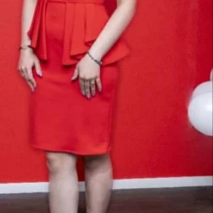 Röd kort klänning med volang - Snygg röd kortklänning med volangdetalj i midjan. Klänningen har en figurnära passform och är perfekt för dig som vill sticka ut. Stilren och trendig design som ger en cool vibe.