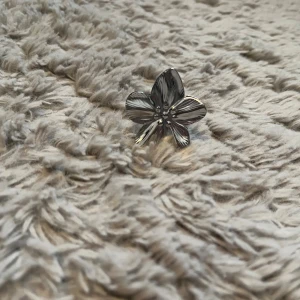 Blommig silverfärgad ring - Cool ring i form av en stor blomma med fem blad, helt i silverfärgad metall. Perfekt statement piece för dig som vill sticka ut med en unik accessoar. Blommans detaljer är snyggt utmejslade och ger ringen en trendig vibe.
