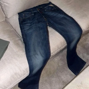 Mörkblå Replay jeans med raka ben - Säljer ett par klassiska mörkblå jeans från Replay med snygga slitningar och raka ben. Jeansen har fem fickor, orangea sömmar och tydlig Replay-patch bak i midjan. Perfekta för dig som gillar en tidlös och avslappnad look. Length 32 waist 30, säljer den för att dem inte passar mig