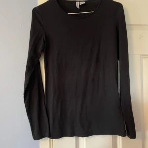 Svart långärmad basic tröja H&M - En enkel svart långärmad tröja från H&M Divided Basic i storlek S. Tröjan har rund halsringning och är gjord i mjuk bomull, perfekt för layering eller chill dagar. Passformen är normal och modellen är klassisk utan detaljer eller mönster.