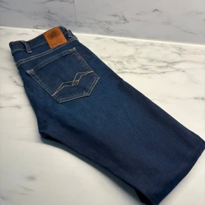 Replay jeans - Säljer ett par snygga Replay jeans i klassisk mörkblå denim. Byxorna har den ikoniska Replay-loggan på bakfickan och en bekväm passform som sitter perfekt!   ✨ Detaljer: 	•	Märke: Replay 	•	Modell: (anbass) 	•	Storlek: (29/32) 	•	Färg: Mörkblå 	•	Passform: Slim fit 	•	Skick: Mycket bra    