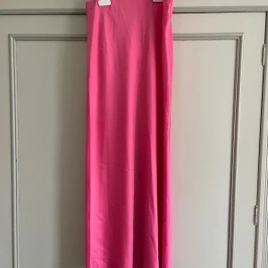 Rosa långkjol från Y.A.S - Säljer en snygg rosa långkjol från Y.A.S i modellen 'XI Column Skirt'. Kjolen har en rak och stilren siluett med bred resår i midjan för extra komfort. Materialet är mjukt och består av 68% återvunnen polyester, 29% polyester och 3% elastan. Perfekt för dig som gillar färgstarka plagg.