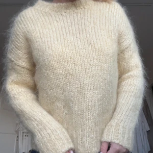 Ljusgul fluffig stickad tröja - Supermysig stickad tröja i ljusgul ton med fluffig känsla. Tröjan har rund hals, långa ärmar och ribbade muddar vid ärmslut och nederkant. Perfekt för dig som gillar en chill och cozy vibe under kyliga dagar.