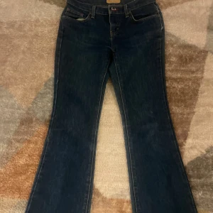 Mörkblå bootcut jeans från Tommy Hilfiger - Snygga mörkblå jeans från Tommy Hilfiger med klassisk bootcut-modell och är lågmidjade. Coola detaljer med färgade ränder på bakfickorna.  Säljer pga att de inte passar mig längre. 
