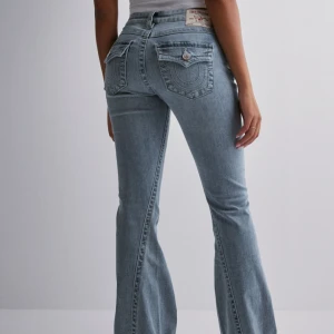 True Religion ljusblå bootcut jeans - Säljer ett par ljusblå jeans från True Religion med bootcut passform och fickdetaljer. Jeansen har låg midja och är tillverkade i mjukt denim med snygga sömmar. Det finns ett hål på insida lår som inte syns när man har på sig dem, men om man vill kan man sy hålet. Annars är de i bra skick! Pris kan diskuteras ❤️