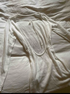 Vit strandklänning - Vit ribbad kortklänning med långa ärmar och en djup öppen rygg. 