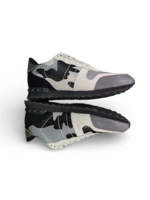 Valentino Rockrunner sneakers camo - Snygga Valentino Rockrunner sneakers med grå, svart och olivgrön camouflage-mönster. Skorna har snörning, platt sula och rund tå. Materialmix av mocka, skinn och syntet. Ikoniska nitar på sulan och cool box med matchande camo-print medföljer.