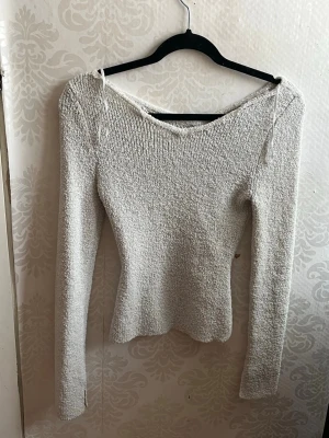 Ljusgrå stickad långärmad tröja - Säljer en ljusgrå stickad tröja med lång ärm och v-ringad hals. Tröjan har en slim passform och är gjord i ett mjukt, strukturerat stickat material. Perfekt för dig som gillar enkla och stilrena plagg med lite extra textur.