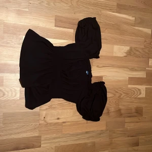 Svart blus med puffärmar Old Navy - Säljer en svart blus från Old Navy i storlek XS. Blusen har puffiga korta ärmar och en smickrande, något croppad passform med rynkade detaljer vid midjan. Perfekt för dig som gillar en feminin och trendig stil.