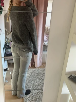 Grå bootcut jeans från Gina Tricot - Säljer ett par grå jeans från Gina Tricot med bootcut-snitt och snygga detaljer på bakfickorna. Jeansen har normal passform och klassisk femficksdesign. Materialet är mjukt denim och färgen är ljusgrå med tvättad look. Perfekt för dig som gillar stilrena och bekväma jeans.
