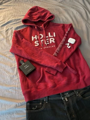 Hollister hoodie - Snygg hollister hoodie i röd färg. Storlek L som passar som ett M. Skicket är fint, använd men inga defekter. Priset kan diskuteras.