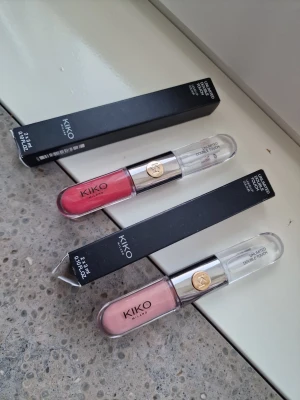 Kiko Milano Unlimited Double Touch läppstift 102 och 110 - Två flytande läppfärger från KIKO Milano, Unlimited Double Touch i nyanserna 110 (rödrosa) och 102 (ljusrosa/nude). Dubbeländad tub med transparent lock och guldfärgad detalj. Ger intensiv färg och glansig finish. Volym: 2 x 3 ml per förpackning. Jag testade endast färgade delar på handen, de är inte använda. 