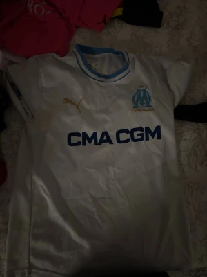 Marseille fotbollströja  - En vit Marseille tröja som är helt ny ! Använd en gång och det va när jag skulle testa den. Den va för liten och säljer den nu för ett rimligt pris !
