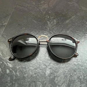 Solglasögon  - Säljer dessa runda solglasögon med svarta glas och tunna guldfärgade skalmar, vid intresse bara att höra av sig! 