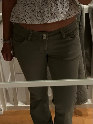 Bootcut gröna byxor med broderade fickor - Snygga gröna bootcut-byxor med dubbla knappar framtill och broderade detaljer på bakfickorna. Byxorna har normal passform och är tillverkade i ett mjukt bomullsmaterial. Perfekta för dig som gillar en klassisk men chill stil.