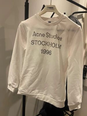 Vit sweatshirt Acne Studios - Säljer en helt ny  vit sweatshirt från Acne.Tröjan har rund hals, långa ärmar och en clean look. Perfekt för dig som gillar stilrena och trendiga plagg med streetkänsla.